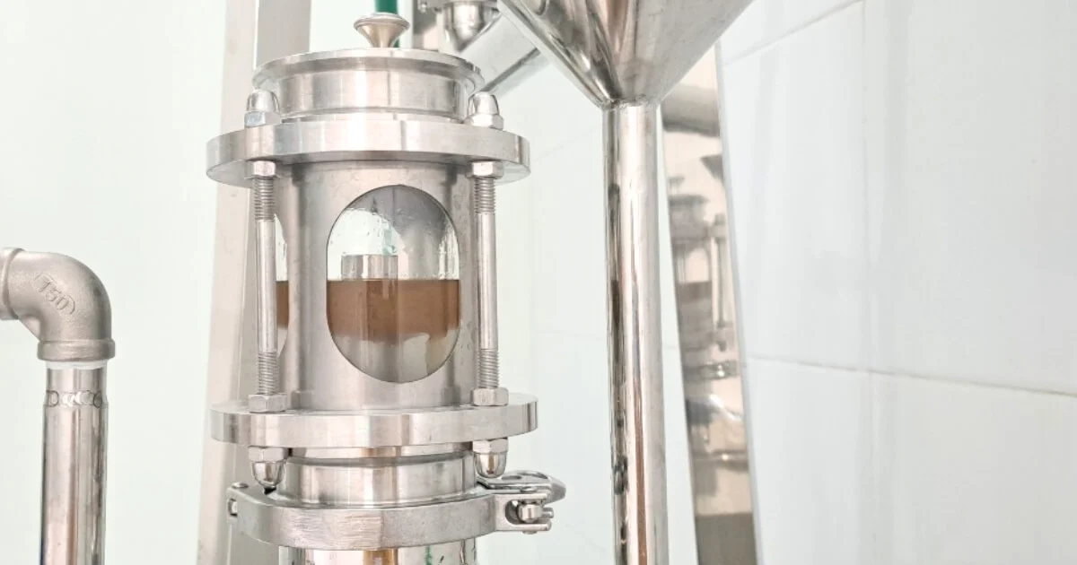 Ống ngắm thiết bị chưng cất cho thấy lớp tinh dầu nổi tách khỏi lớp nước cất cỏ Vetiver bên dưới